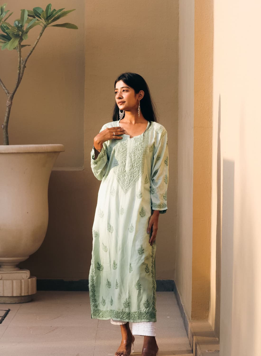 Model wearing a hand-embroidered chikankari kurta in a sunlit courtyard